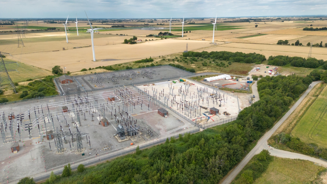 Aerial view of a substation with wind turbines in an adjoining field