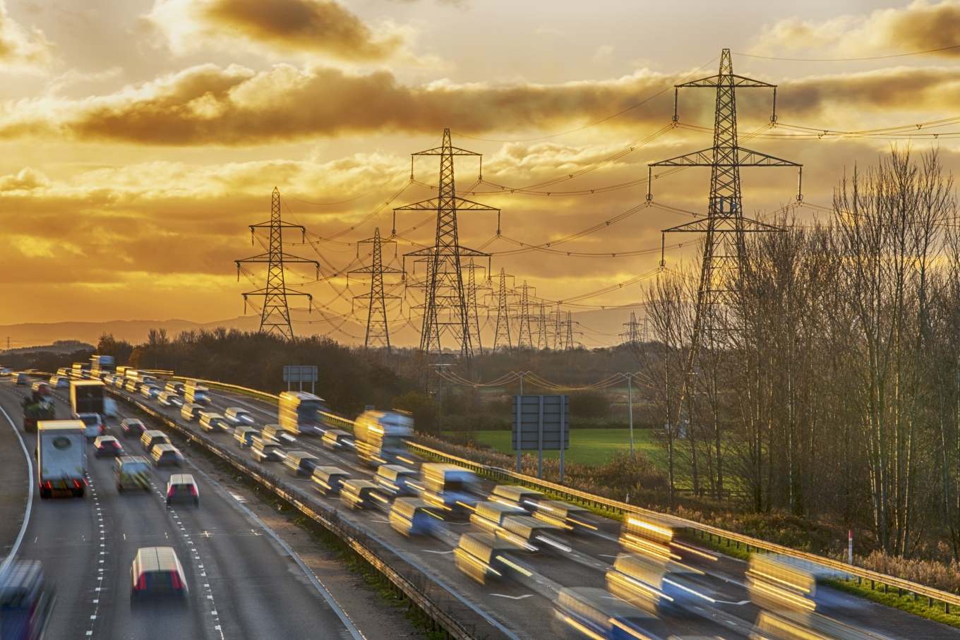Cars driving along a motorway with pylons in the background