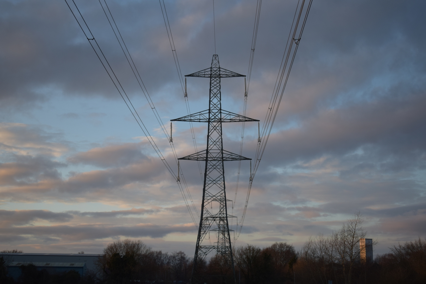 an overhead line pylon with clouds in the background